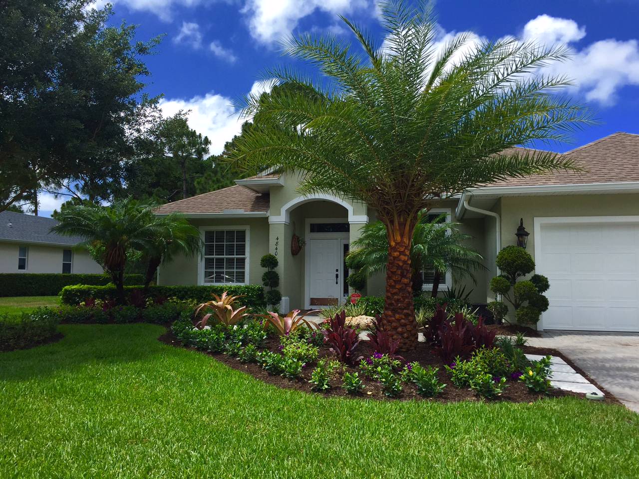 Florida home with tropical landscaping and palm tree in the front yard